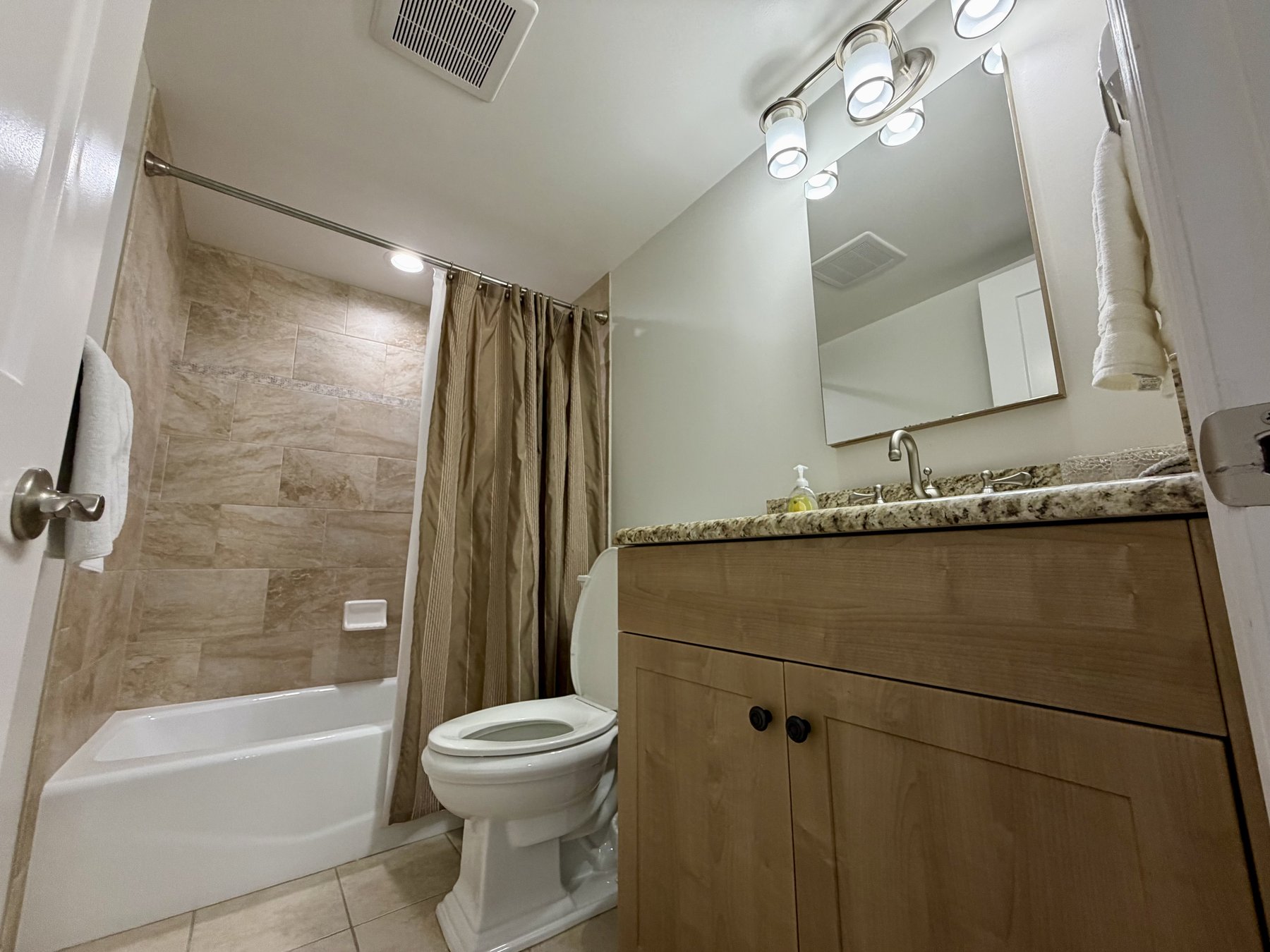 Primary bathroom tub and shower in rental unit 1003